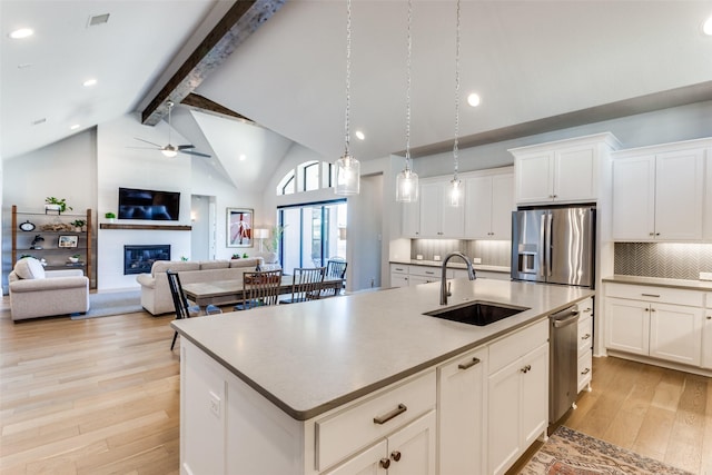 kitchen featuring light wood-style flooring, a fireplace, stainless steel fridge with ice dispenser, a sink, and beamed ceiling