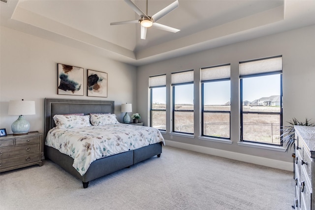 bedroom featuring a tray ceiling, baseboards, light colored carpet, and ceiling fan