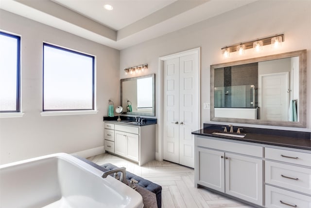 bathroom with a soaking tub, a shower stall, a sink, and two vanities