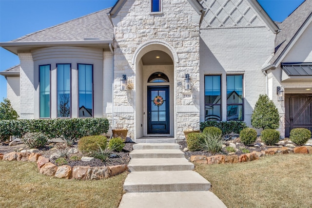 property entrance with brick siding, stone siding, and roof with shingles