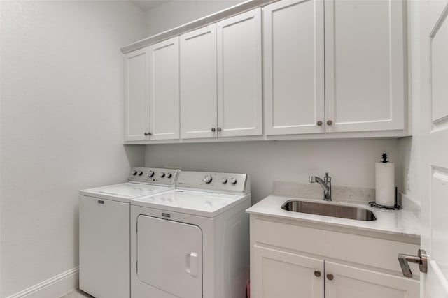 washroom featuring washing machine and clothes dryer, cabinet space, baseboards, and a sink