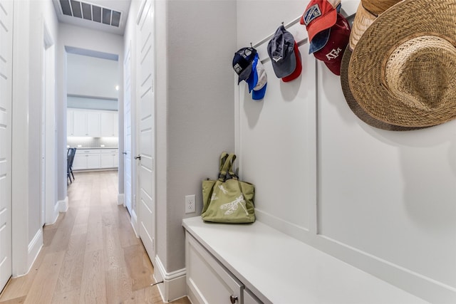 mudroom featuring light wood-style flooring, baseboards, and visible vents