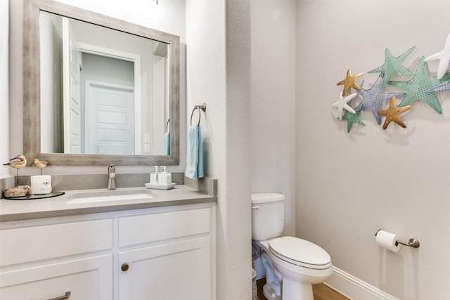 bathroom with vanity, toilet, and baseboards