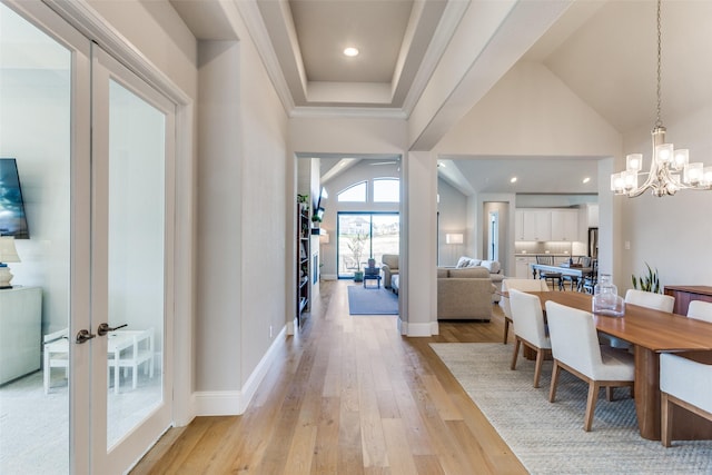 dining area featuring light wood finished floors, a chandelier, ornamental molding, vaulted ceiling, and french doors