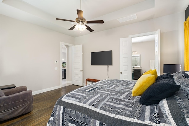 bedroom featuring visible vents, dark wood-type flooring, a ceiling fan, ensuite bath, and baseboards