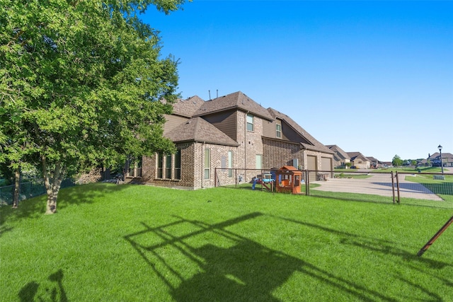 view of side of property featuring a yard, fence, brick siding, and a playground