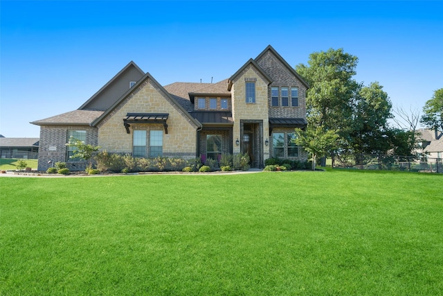 view of front of home with a standing seam roof, fence, roof with shingles, a front yard, and metal roof