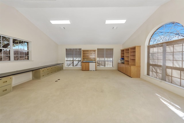 unfurnished living room with high vaulted ceiling and light carpet