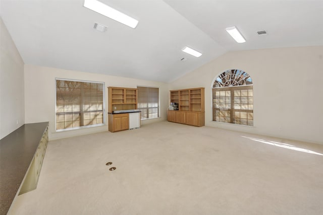 unfurnished living room featuring lofted ceiling, plenty of natural light, and visible vents