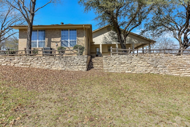 back of house with brick siding and a lawn