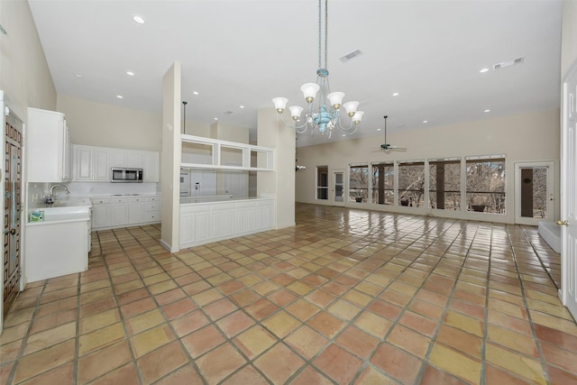 unfurnished living room featuring a high ceiling, light tile patterned flooring, visible vents, and a sink