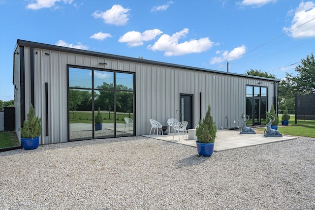 rear view of house featuring board and batten siding and a patio