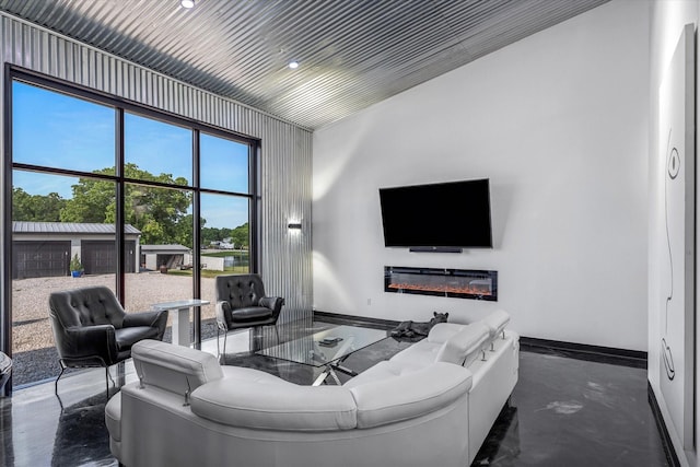 living area featuring a glass covered fireplace and baseboards