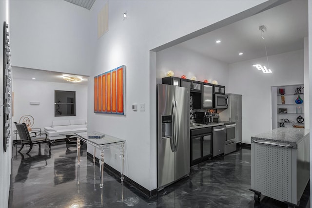 kitchen with pendant lighting, light stone counters, a towering ceiling, and stainless steel appliances