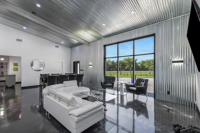 living room with visible vents, concrete floors, and high vaulted ceiling