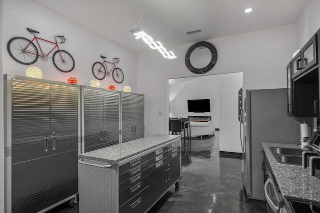 kitchen with a center island, visible vents, finished concrete flooring, and dark cabinets