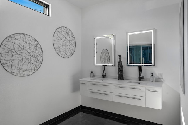 bathroom with a sink, concrete floors, baseboards, and double vanity