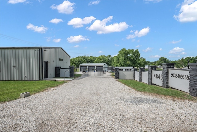 view of gate featuring an outbuilding, a pole building, and fence