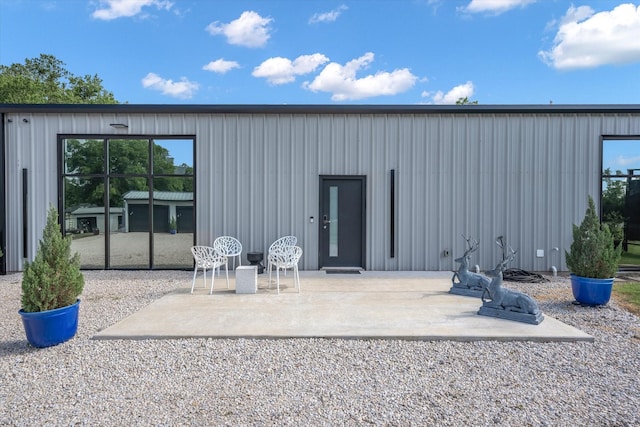 rear view of property with board and batten siding and a patio area