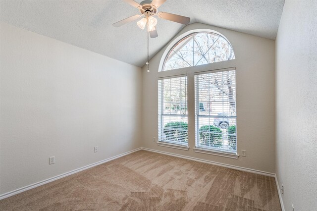 carpeted spare room with ceiling fan, lofted ceiling, a healthy amount of sunlight, and a textured ceiling