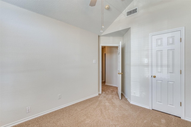 unfurnished bedroom featuring visible vents, baseboards, vaulted ceiling, light carpet, and a textured ceiling