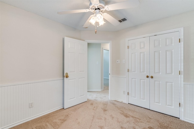 unfurnished bedroom featuring a closet, visible vents, wainscoting, and carpet