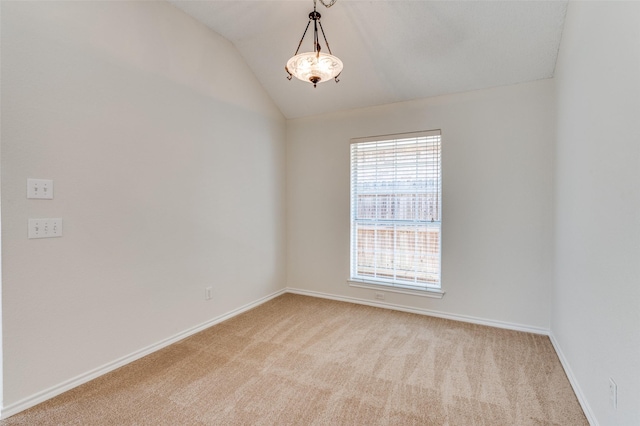 empty room featuring lofted ceiling, light colored carpet, and baseboards