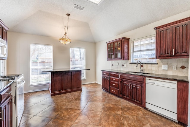 kitchen featuring dark countertops, visible vents, vaulted ceiling, white appliances, and a sink