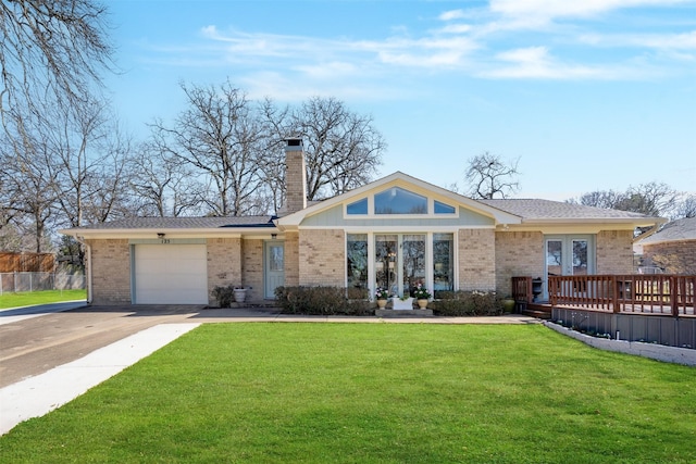 view of front of home with brick siding, driveway, a chimney, and a front lawn