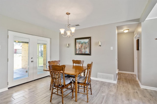 dining area featuring light wood finished floors, visible vents, baseboards, and a notable chandelier