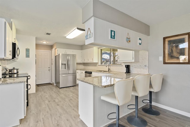 kitchen with a peninsula, light stone countertops, backsplash, and stainless steel appliances