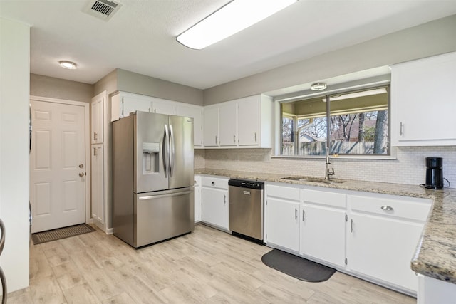 kitchen with visible vents, white cabinets, stainless steel appliances, and a sink