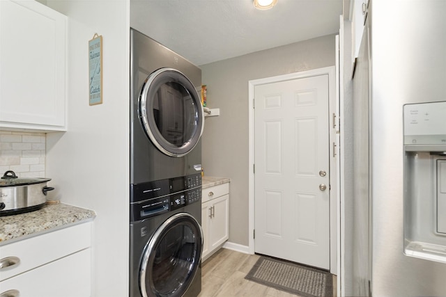 clothes washing area with stacked washer / dryer and light wood-type flooring