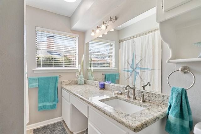 bathroom featuring curtained shower, baseboards, and vanity