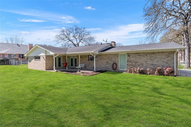 back of house with a yard, brick siding, a chimney, and fence