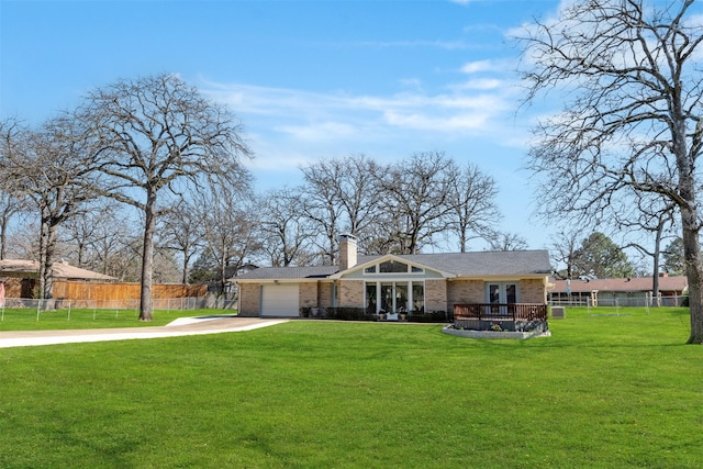 view of front facade with a front yard, concrete driveway, fence, and brick siding