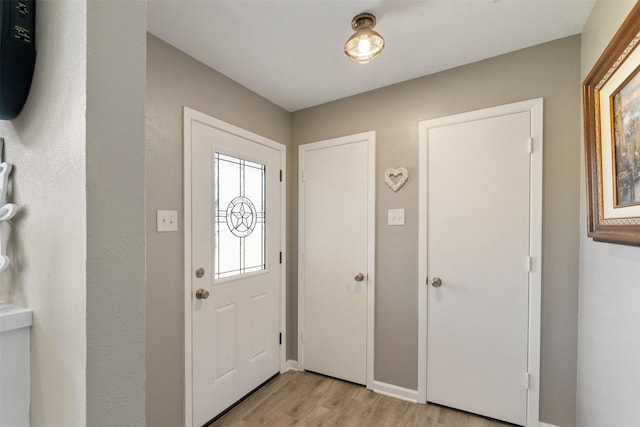 foyer entrance featuring light wood finished floors and baseboards