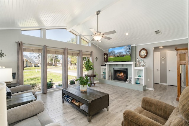 living area with visible vents, a brick fireplace, vaulted ceiling with beams, baseboards, and light wood-type flooring