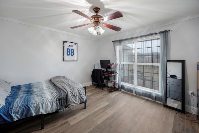 bedroom with ceiling fan, baseboards, wood finished floors, and crown molding