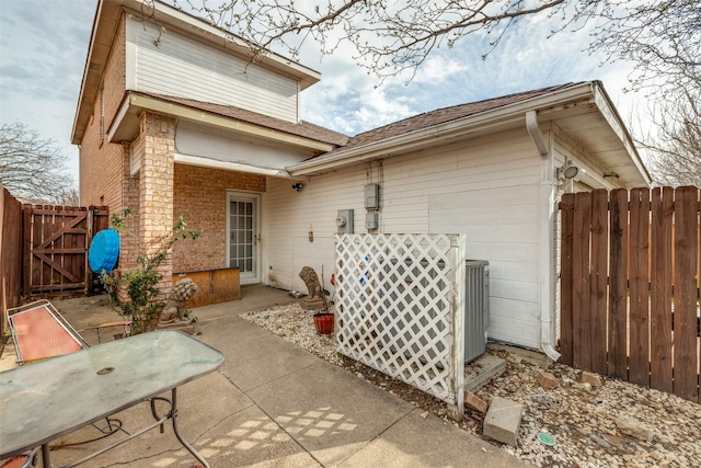 rear view of house featuring a gate, a patio, fence, an attached garage, and brick siding