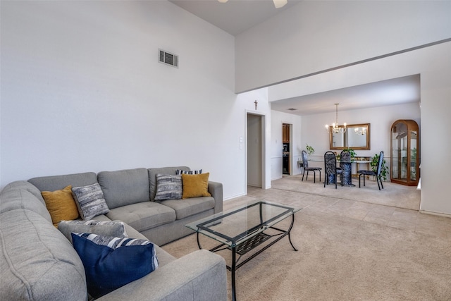 living area featuring visible vents, baseboards, a chandelier, light carpet, and a towering ceiling