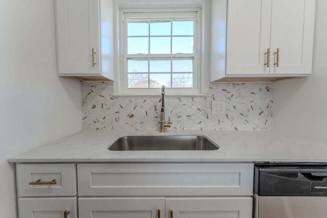 kitchen with a sink, decorative backsplash, stainless steel dishwasher, and white cabinetry