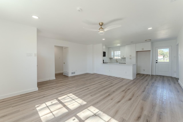 unfurnished living room featuring a wealth of natural light, baseboards, ceiling fan, and light wood finished floors