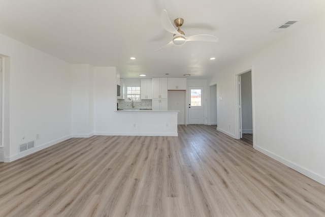 unfurnished living room featuring light wood finished floors, visible vents, and baseboards