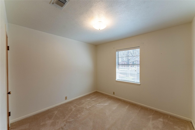 empty room with light carpet, visible vents, a textured ceiling, and baseboards