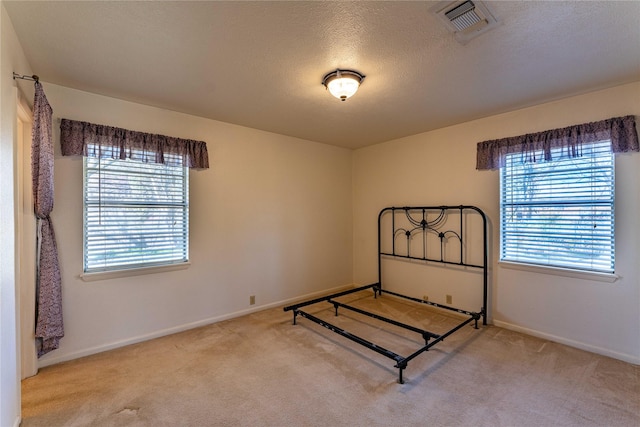 carpeted bedroom featuring visible vents, multiple windows, a textured ceiling, and baseboards