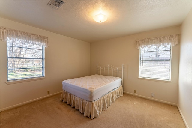 bedroom with visible vents, light carpet, multiple windows, and baseboards