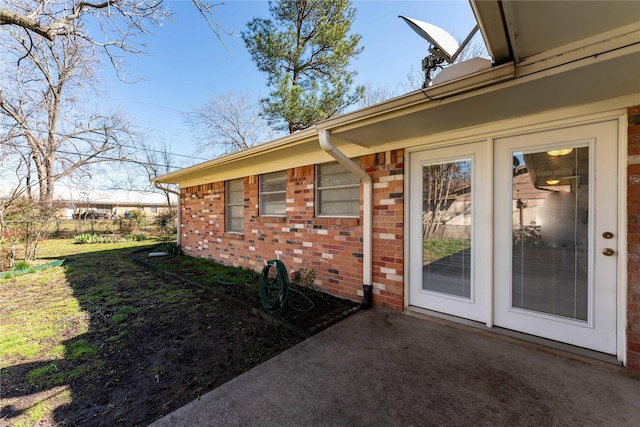 doorway to property with brick siding and a patio area