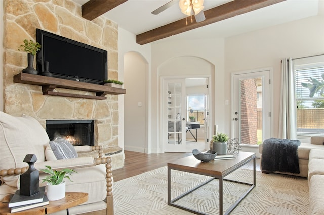 231 Archer Way, Forney, TX 75126 - living room featuring ceiling fan, beam ceiling, a stone fireplace, wood finished floors, and arched walkways