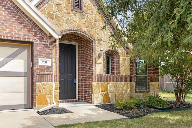 view of exterior entry with brick siding, stone siding, and an attached garage